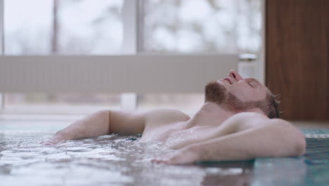 relax-in-wellness-and-spa-center-after-work-adult-caucasian-man-is-lying-in-warm-water-of-pool